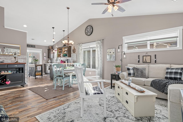 living room with ceiling fan with notable chandelier, light hardwood / wood-style floors, and lofted ceiling