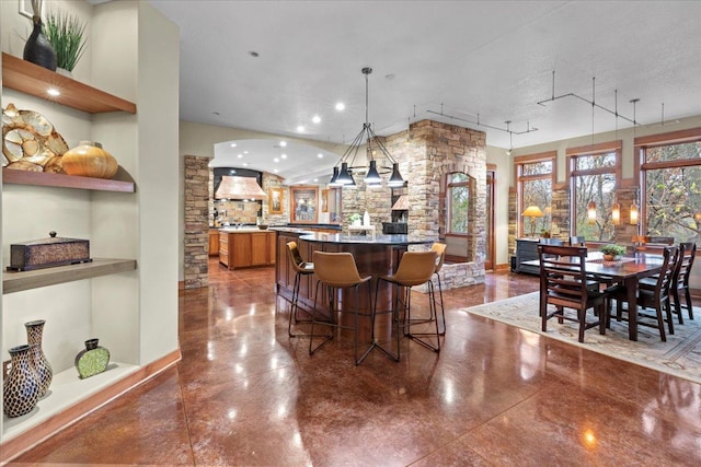 kitchen featuring a breakfast bar, hanging light fixtures, custom range hood, and a textured ceiling