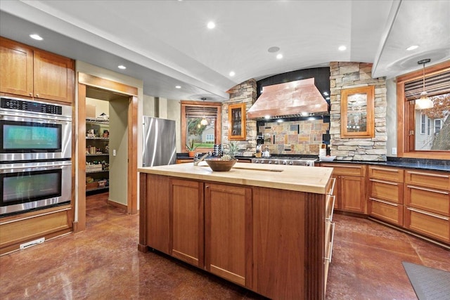 kitchen featuring double oven, wooden counters, decorative light fixtures, custom range hood, and a center island