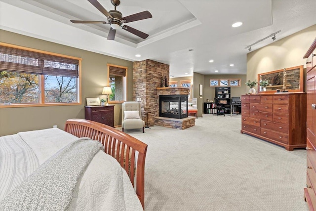 carpeted bedroom featuring a fireplace, a tray ceiling, and track lighting