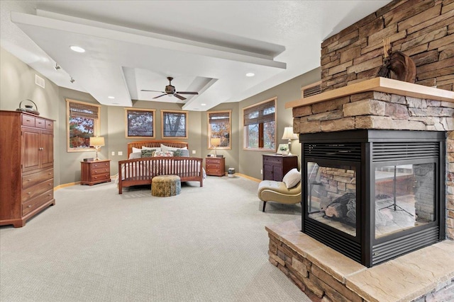 bedroom with a stone fireplace, carpet, and a raised ceiling