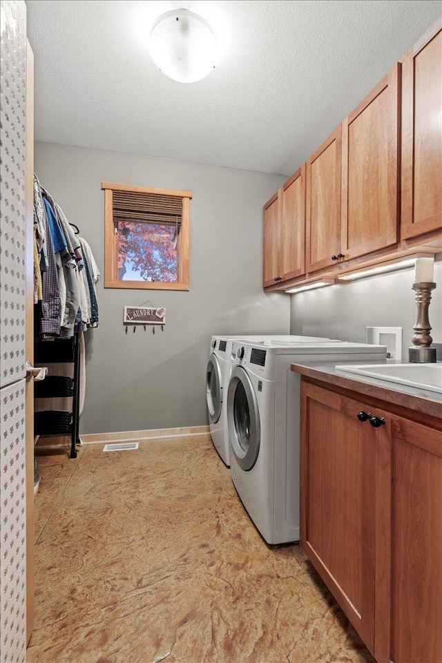 washroom featuring sink, independent washer and dryer, cabinets, and a textured ceiling