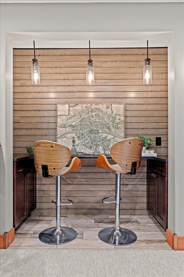 bar featuring decorative light fixtures and wooden walls