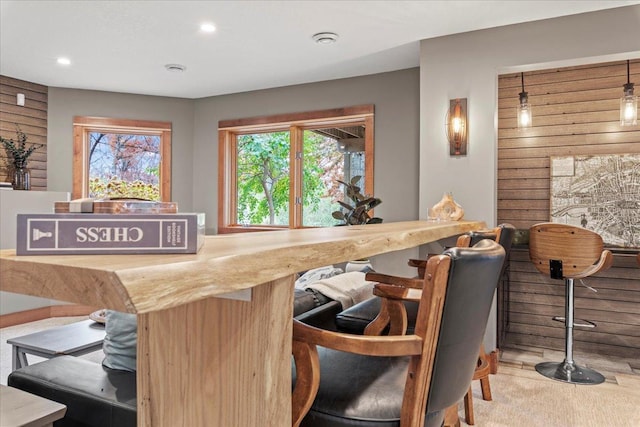 bar with wooden walls, pendant lighting, and light carpet