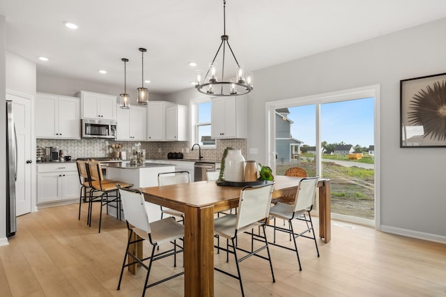 dining room featuring sink, a chandelier, and light hardwood / wood-style flooring