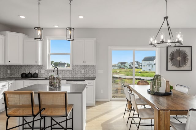 kitchen featuring white cabinetry, sink, decorative light fixtures, and a notable chandelier