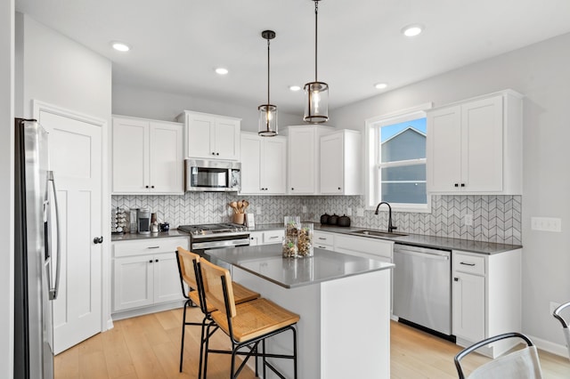 kitchen with pendant lighting, a center island, sink, white cabinetry, and stainless steel appliances