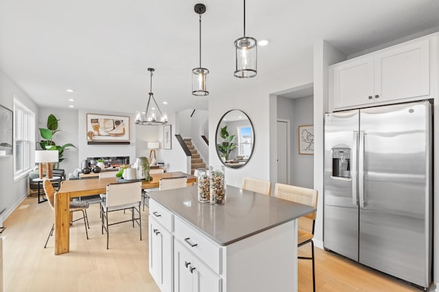 kitchen with a center island, stainless steel fridge, pendant lighting, white cabinets, and light wood-type flooring