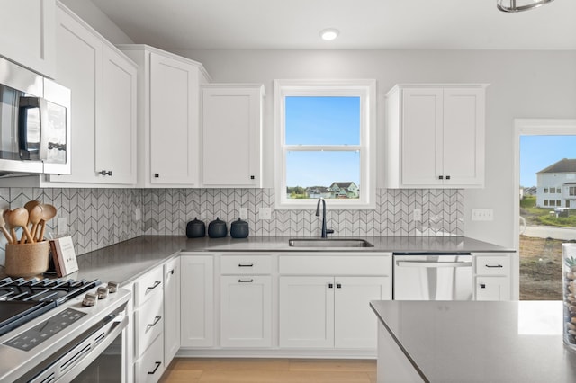 kitchen with decorative backsplash, appliances with stainless steel finishes, white cabinetry, and sink