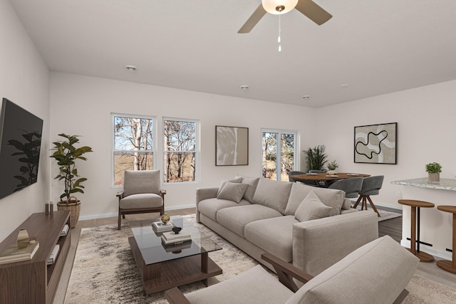 living area featuring a ceiling fan, a healthy amount of sunlight, baseboards, and wood finished floors