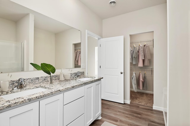 bathroom featuring double vanity, baseboards, a sink, and wood finished floors