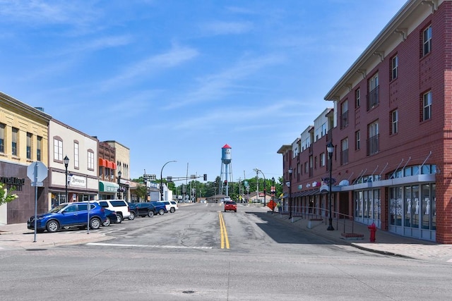 view of road featuring sidewalks, street lighting, traffic signs, and curbs