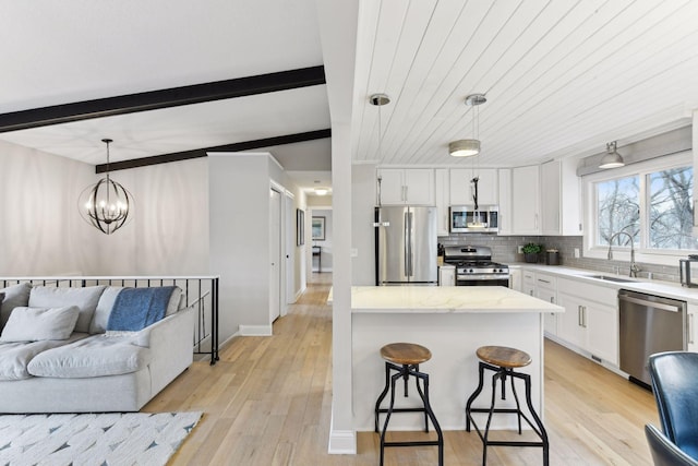 kitchen featuring white cabinets, sink, hanging light fixtures, beamed ceiling, and stainless steel appliances