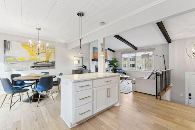 kitchen with an inviting chandelier, hanging light fixtures, light hardwood / wood-style flooring, beam ceiling, and white cabinetry