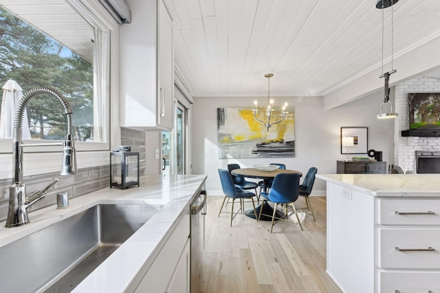 kitchen with sink, hanging light fixtures, a fireplace, white cabinetry, and wood ceiling