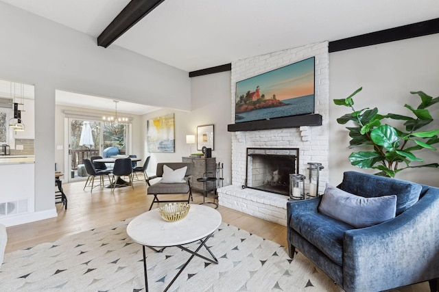 living room with sink, a brick fireplace, beamed ceiling, a notable chandelier, and light wood-type flooring