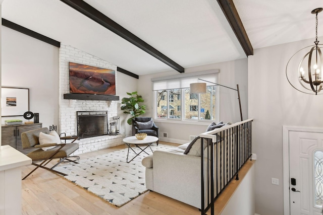 living room with a fireplace, lofted ceiling with beams, light hardwood / wood-style flooring, and a notable chandelier