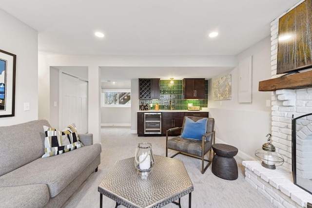 carpeted living room featuring a fireplace, wine cooler, and bar