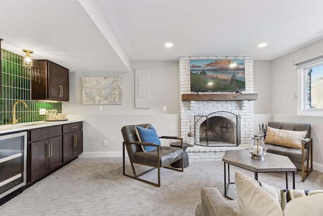 living room featuring light carpet, sink, beverage cooler, and a brick fireplace