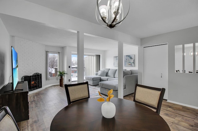 dining space with wood-type flooring, a fireplace, and a chandelier