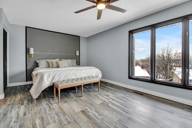 bedroom with ceiling fan, hardwood / wood-style flooring, and a textured ceiling