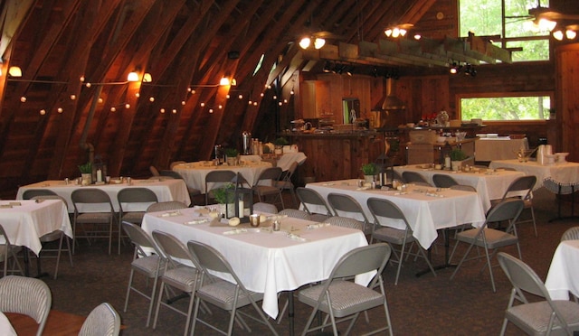 dining room featuring vaulted ceiling and wooden walls