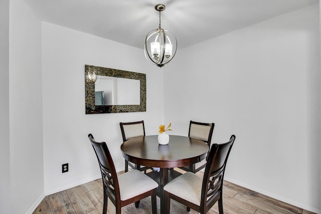 dining room featuring light wood-style floors, a chandelier, and baseboards