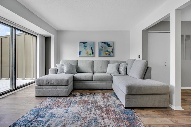 living area with a textured ceiling, baseboards, and wood finished floors