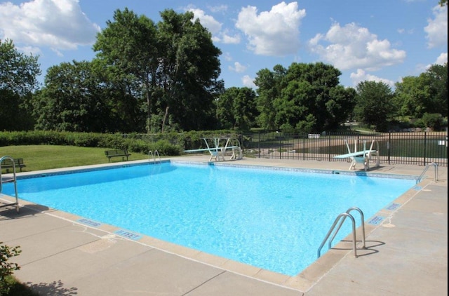 community pool featuring fence, a lawn, and a patio