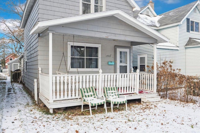 snow covered property entrance with a porch