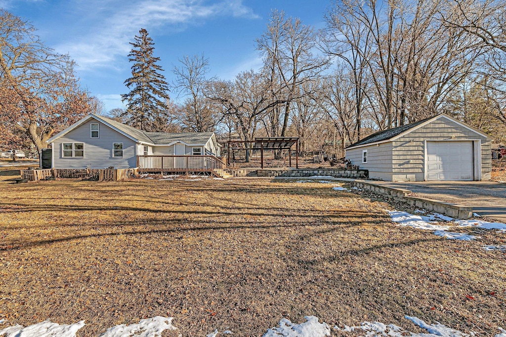 yard layered in snow with an outdoor structure, a garage, and a deck