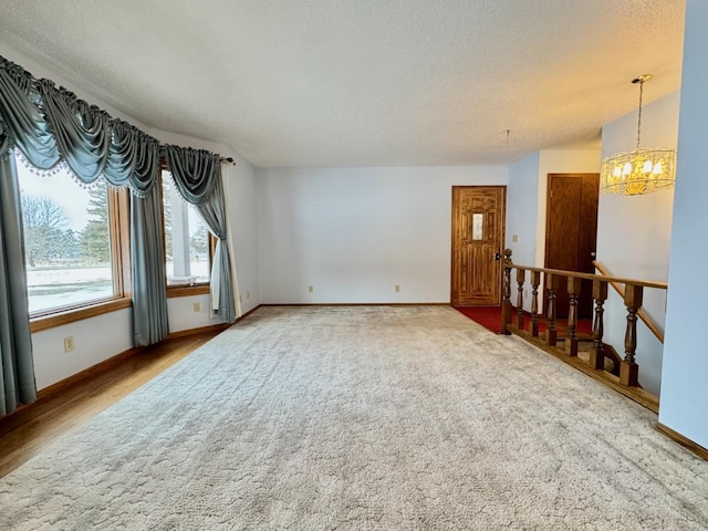 carpeted empty room with a textured ceiling and a notable chandelier