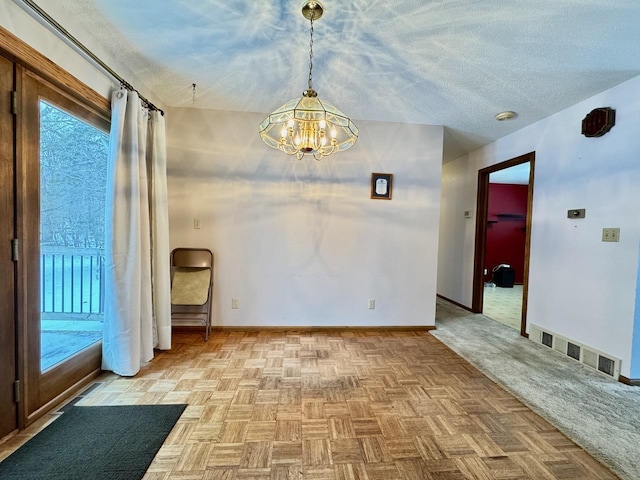 empty room with light parquet floors, a chandelier, and a textured ceiling