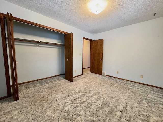 unfurnished bedroom featuring a textured ceiling, light carpet, and a closet