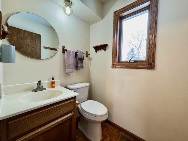 bathroom with vanity, toilet, and parquet floors