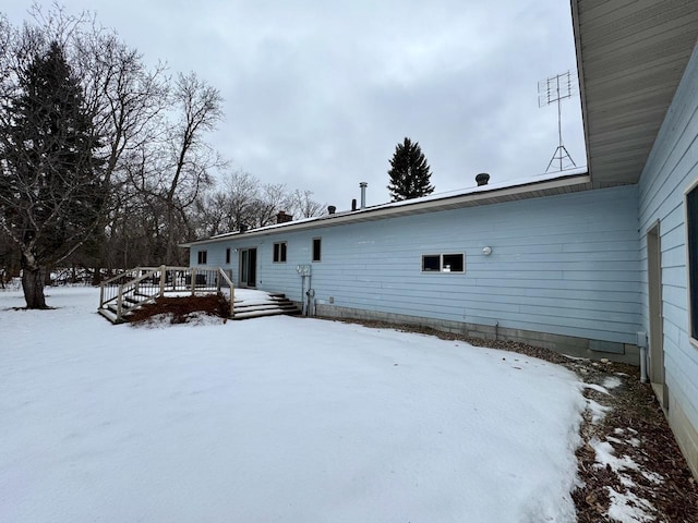 snow covered back of property with a deck