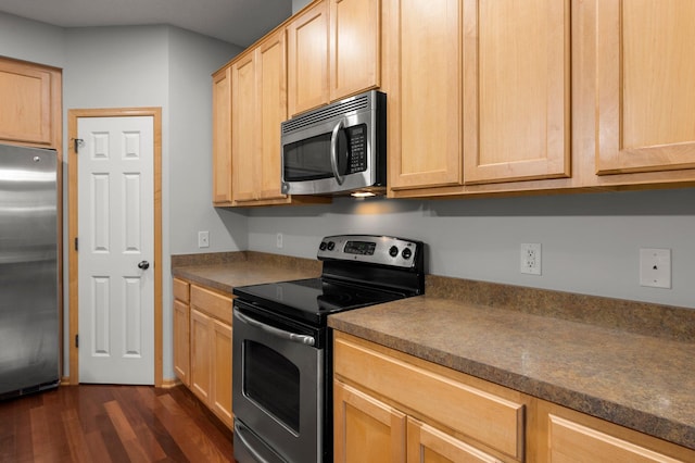 kitchen featuring dark wood-style floors, light brown cabinetry, appliances with stainless steel finishes, and dark countertops