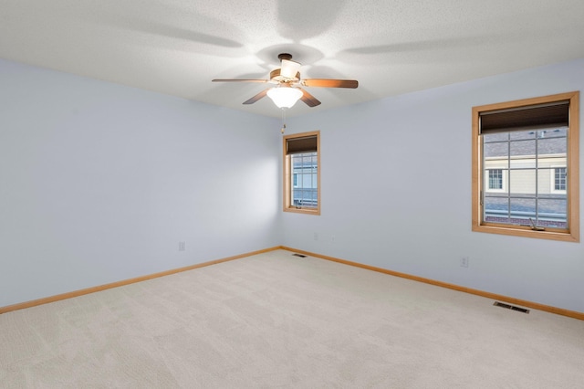 empty room with light carpet, visible vents, a wealth of natural light, and baseboards