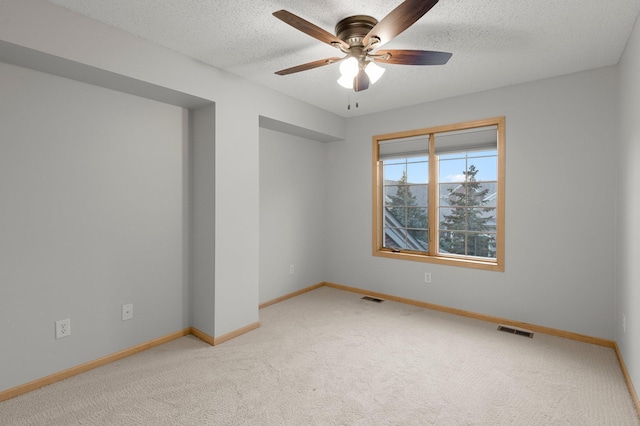 unfurnished room with light carpet, a textured ceiling, visible vents, and baseboards