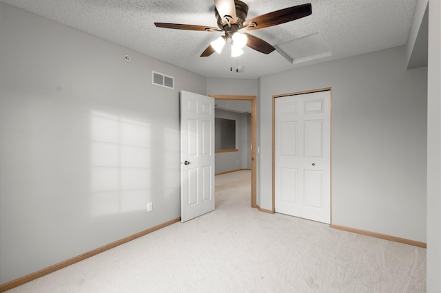 unfurnished bedroom featuring light carpet, attic access, visible vents, and a textured ceiling