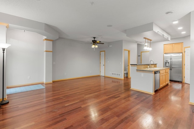 kitchen with stainless steel appliances, visible vents, hanging light fixtures, open floor plan, and an island with sink