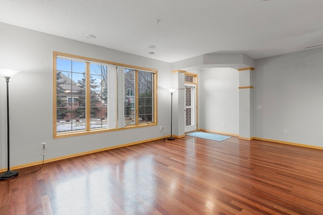 unfurnished room with light wood-style flooring, baseboards, and a textured ceiling