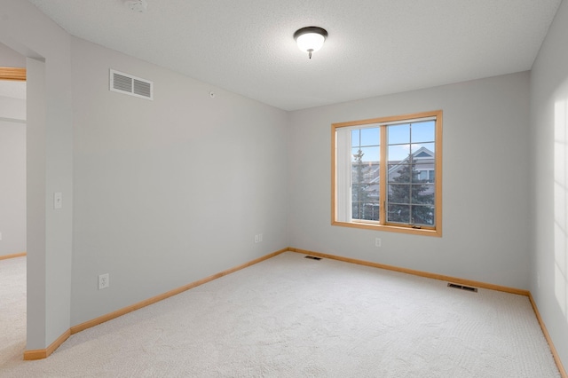 spare room with carpet, visible vents, a textured ceiling, and baseboards