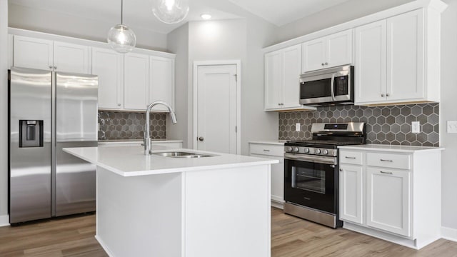 kitchen with sink, decorative light fixtures, a kitchen island with sink, white cabinets, and appliances with stainless steel finishes