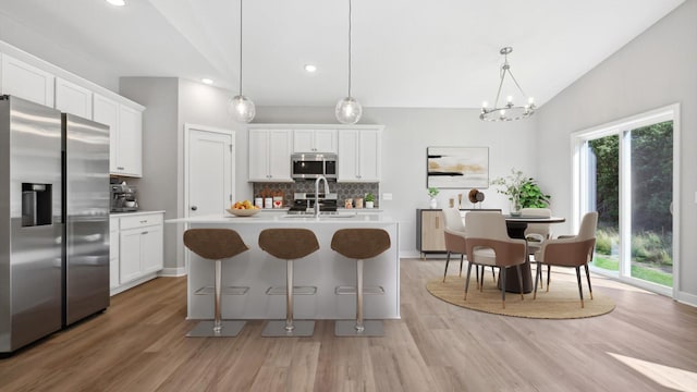 kitchen with white cabinetry, hanging light fixtures, and appliances with stainless steel finishes