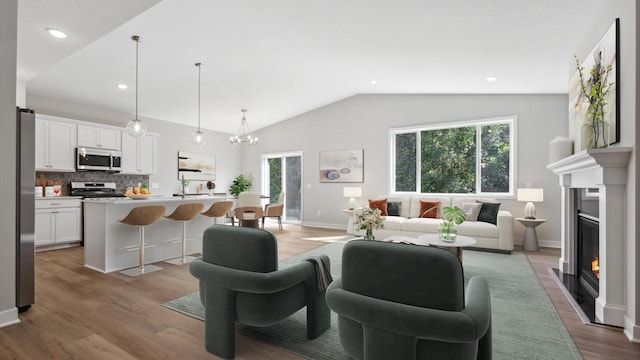 living room featuring light wood-type flooring, lofted ceiling, and a chandelier