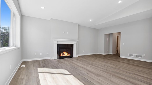 unfurnished living room featuring lofted ceiling and light wood-type flooring