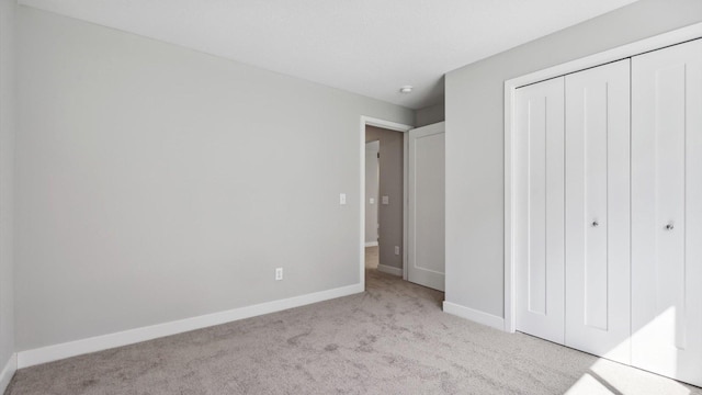 unfurnished bedroom featuring light carpet and a closet