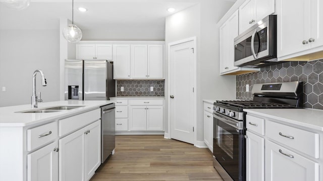 kitchen with white cabinetry, sink, stainless steel appliances, tasteful backsplash, and decorative light fixtures