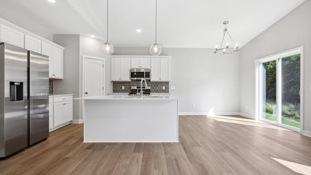 kitchen with appliances with stainless steel finishes, decorative light fixtures, and white cabinetry